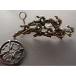 A steeple chase horse racing brooch in silver, the pierced relief showing jockey, horses reins and