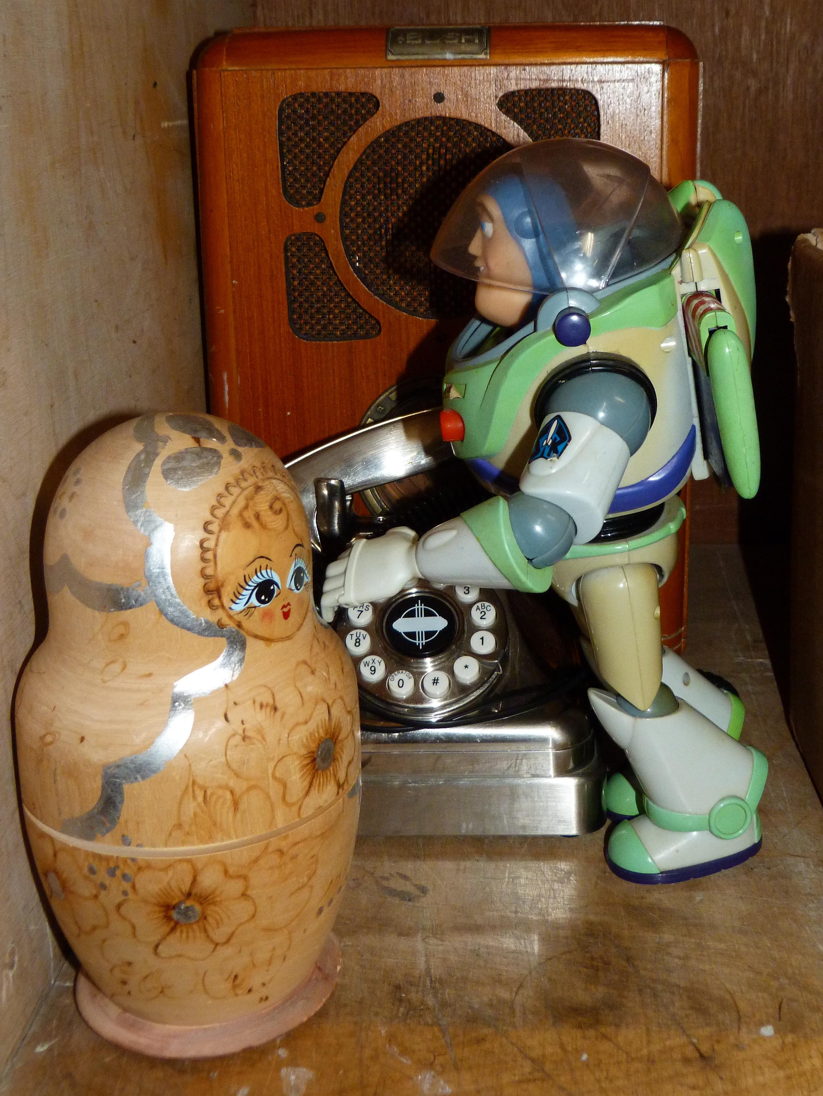 A retro style wireless, a vintage style phone, a Buzz Lightyear figure and a Russian doll
