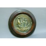 An early 20th century brass plaque cast as a sailing ship within rope twist border, mahogany stained