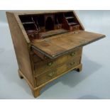 A reproduction walnut miniature bureau in George III style, the fall flap revealing stepped fitted