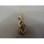 A pendant and chain in 9ct gold, the open ribbon scroll claw and grain set with small eight cut