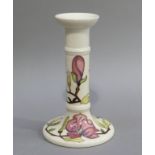 A Moorcroft candlestick, the cream ground tube lined and painted in pink, mauve and green with