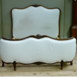 A continental walnut frame double bedstead with upholstered head and curved footboard the encircling