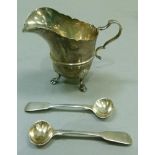 A silver helmet cream jug on three hoof feet, London 1924; together with a pair of Georgian