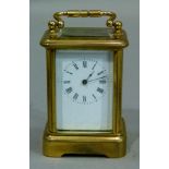 A miniature brass carriage clock by Harrods having a white enamel dial with black Roman numerals,