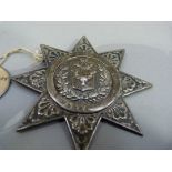 A Victorian silver badge (Highlanders) embossed with shield beneath a ribbon tied horn, tied oak