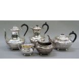 A four piece tea service of half reeded design with ebonised handles comprising teapot, hot water