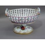 A German porcelain two handled pedestal basket encrusted with flowers, the well painted with