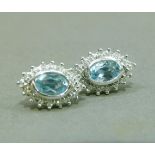 A pair of diamond and blue topaz earrings in 9ct gold each collet set to the centre with an oval