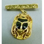 A scarab pendant onyx set with filigree legs raised against an oval plate with hieroglyph reliefs to