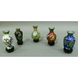 A box containing five small cloisonne vases different shaped and colours, each with a small hardwood