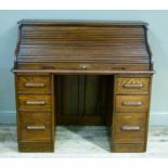 An early 20th century oak rolled top desk, the interior fitted with pigeon holes and drawers above