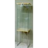 A two door glass display cabinet raised on tubular metal supports