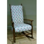 An early 20th century elm rocking chair having a ladder back and spindle arms upholstered pad to the