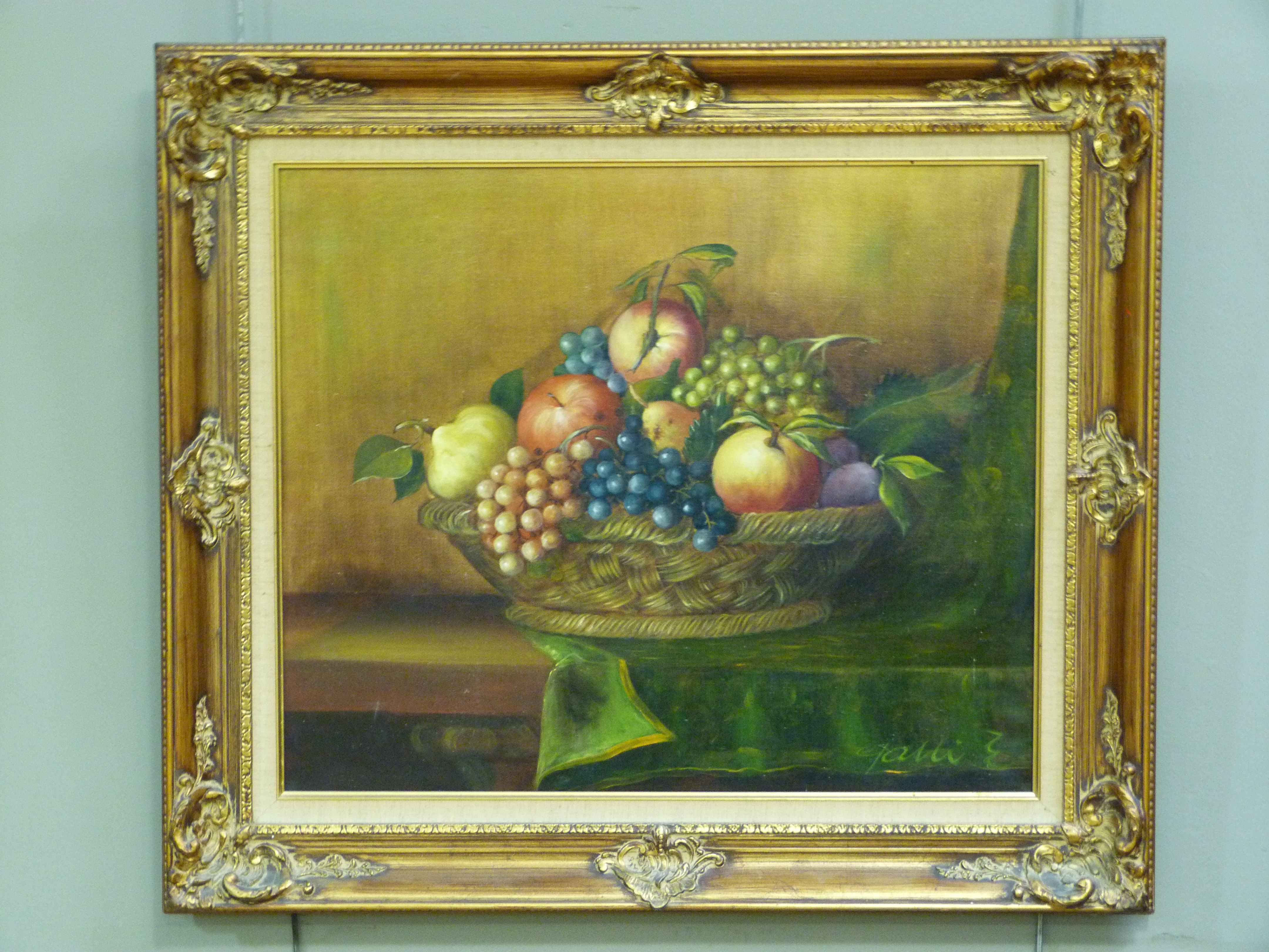 A still life basket of fruit upon a table, oil on canvas, indistinctly signed to lower right