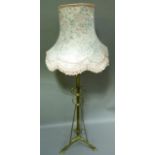 A Victorian brass standard lamp with scrolled supports and on tripod legs complete with shade