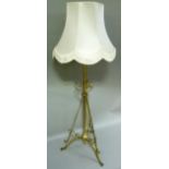 A late Victorian brass standard lamp with three scroll top supports and tripod feet
