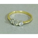 A three stone diamond ring in 18ct gold, the graduated brilliant cut stones collet set inline, total