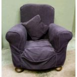 An Edwardian armchair with loose purple dralon cover compressed bun feet