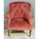 An Edwardian deep salmon button upholstered tub chair on square tapered legs and ceramic castors
