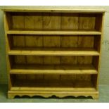 A pine open bookshelf with shaped base bracket feet, 136cm wide x 135cm high