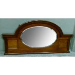 A mahogany mirror back of arched form with moulded cornice and fluted frame, the oval bevelled plate