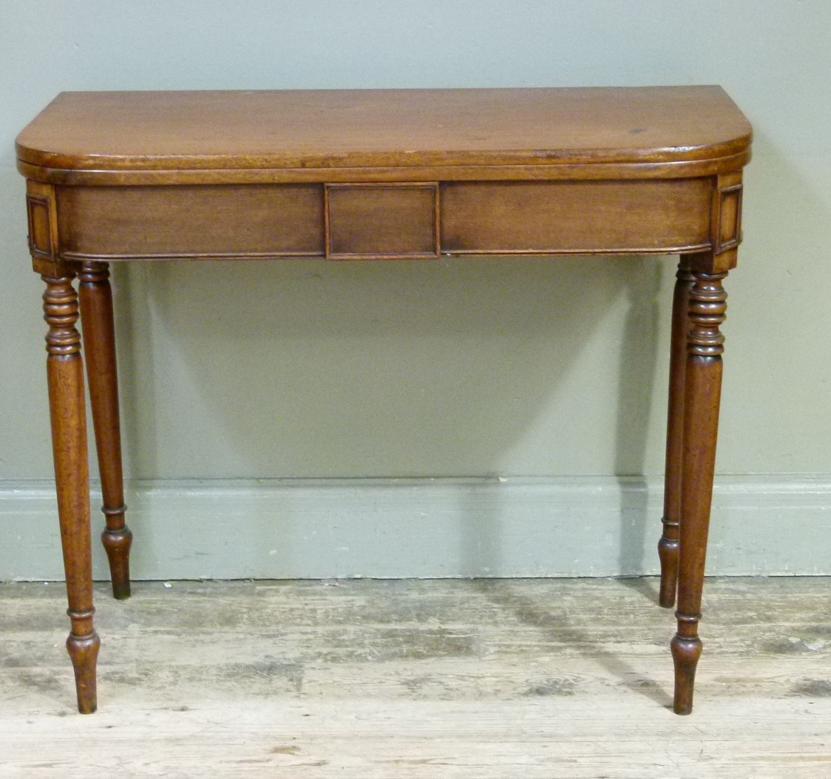 A Victorian mahogany foldover tea table with centre tablet to the frieze and on turned legs