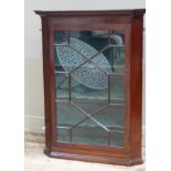 An early 20th century mahogany corner hanging cupboard, having a dentil moulded cornice above a