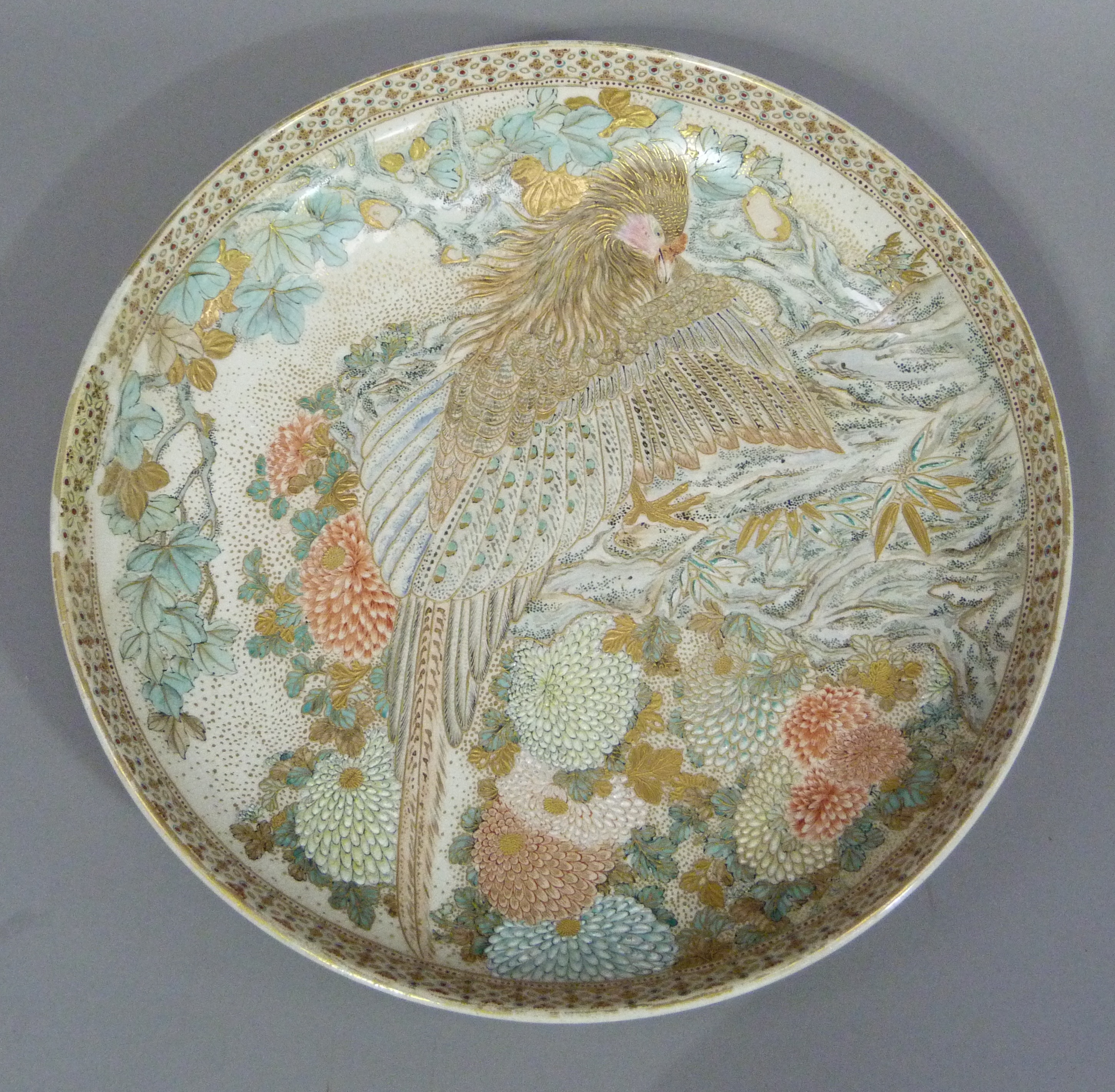 A Japanese Satsuma charger decorated with an exotic bird amidst chysanthemums, 31cm diameter