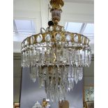 A four tier basket chandelier hung with prismatic drops on a gilt metal frame