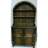 An oak dresser with arched shelved back the base fitted with two short drawers above two panelled