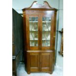 An Edwardian mahogany standing corner cupboard having a broken neck pediment above tracery glazed