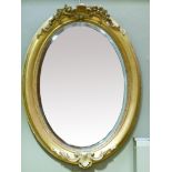 An Edward VII oval bevelled wall mirror in giltwood frame with shell and foliate cresting and apron