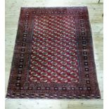 A large Bokhara rug the field with five rows of medallions on a red ground within claret borders