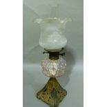 A late Victorian oil lamp, the cast metal base of pierced swirl decoration, the reservoir of