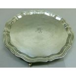 An Elizabeth II silver salver, circular with pie crust rim on three knurled feet, engraved with