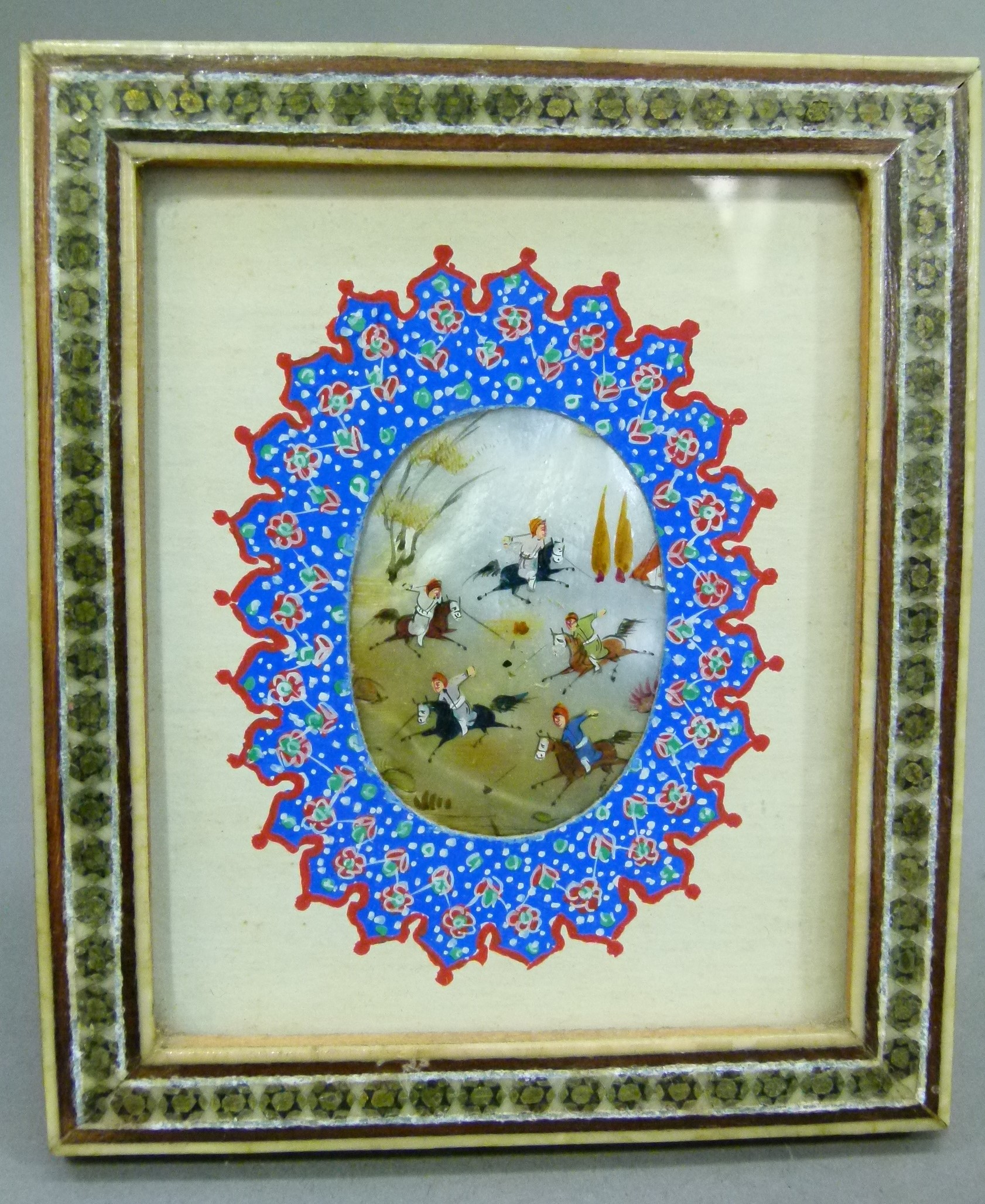 A Persian miniature, the oval shell painted with figures on horseback within a landscape, within a