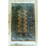 A small Bokhara style rug the salmon ground with a row of oval medallions, within multiple