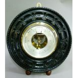 An Aneroid barometer in a dark wood carved frame
