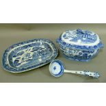 A blue and white willow pattern meat dish and a soup tureen cover and associated ladle