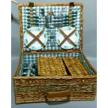 A wicker picnic hamper for four people containing plates, cutlery, condiments, corkscrew, thermos