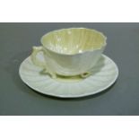 A Belleek nautilus cup and saucer, the shell shaped cup resting on a moulded circular saucer, saucer