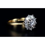 A DIAMOND CLUSTER RING in 18ct yellow and white gold, claw set to the centre with a brilliant cut
