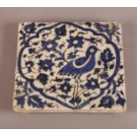 AN IRANIAN BLUE AND WHITE POTTERY TILE, Qajar of square form decorated with a bird amidst