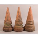 A SET OF THREE 19TH CENTURY TERRACOTTA FINIALS of conical and writhen form on circular plinth