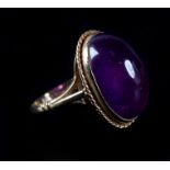 AN AMETHYST DRESS RING in 9ct gold, the oval cabochon stone collet set within a twisted wire