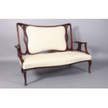 AN EDWARD VII MAHOGANY OCCASIONAL SETTEE having an upholstered back and seat the encircling frame
