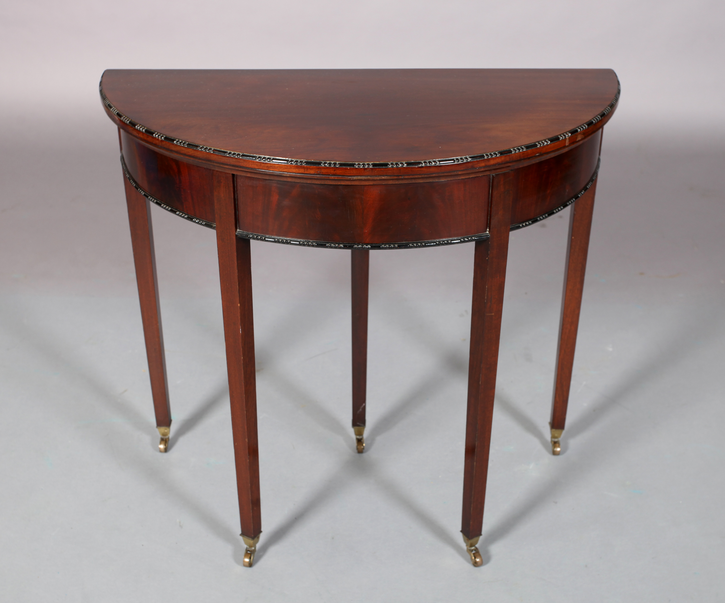 AN EDWARD VII MAHOGANY CARD TABLE in George III style, the D-shaped top with bead and reel carved