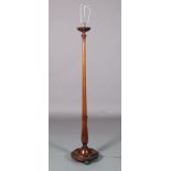 A MAHOGANY STANDARD LAMP, 1920s, having a lobed cup collar, tapered column with applied leafage on a