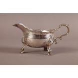 A GEORGE III SILVER SAUCEBOAT, London 1776, having a bracketed rim, leaf capped scroll handle and on